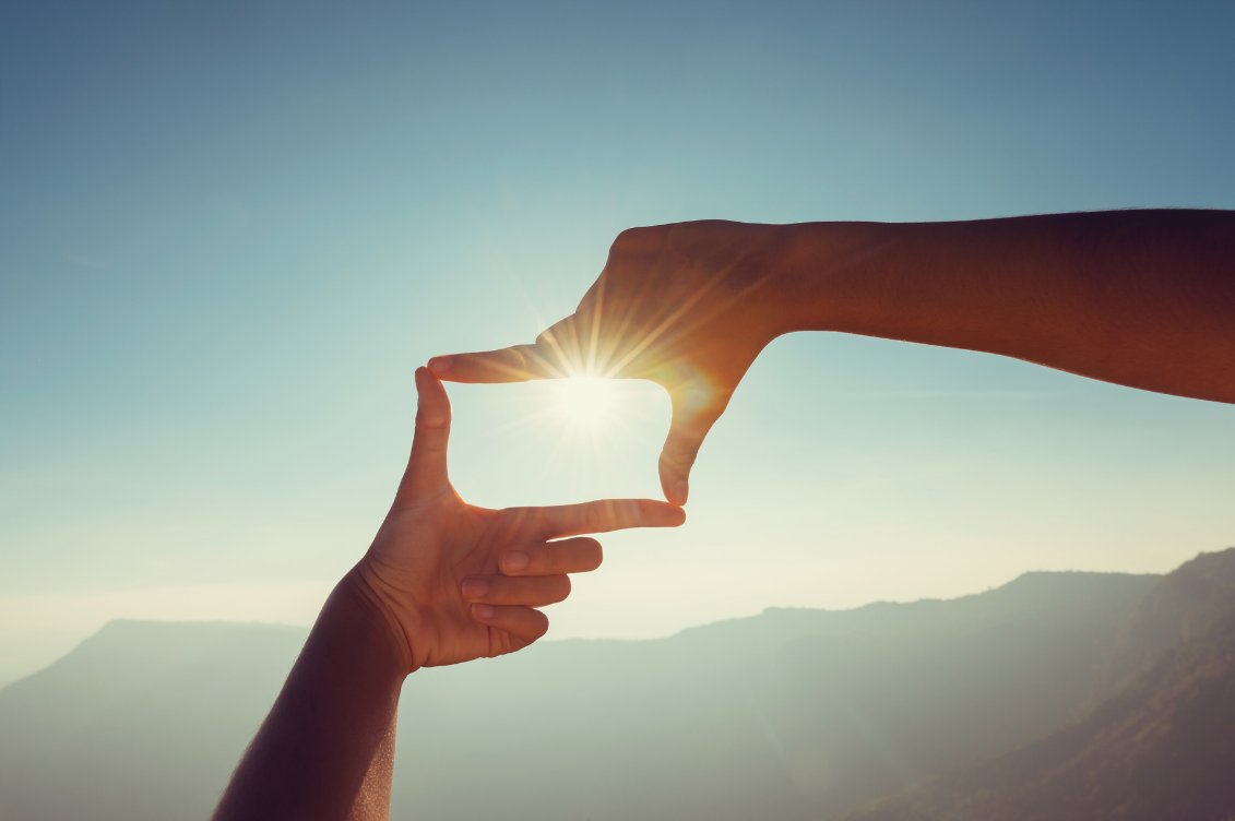 Hands framing the sun at sunset